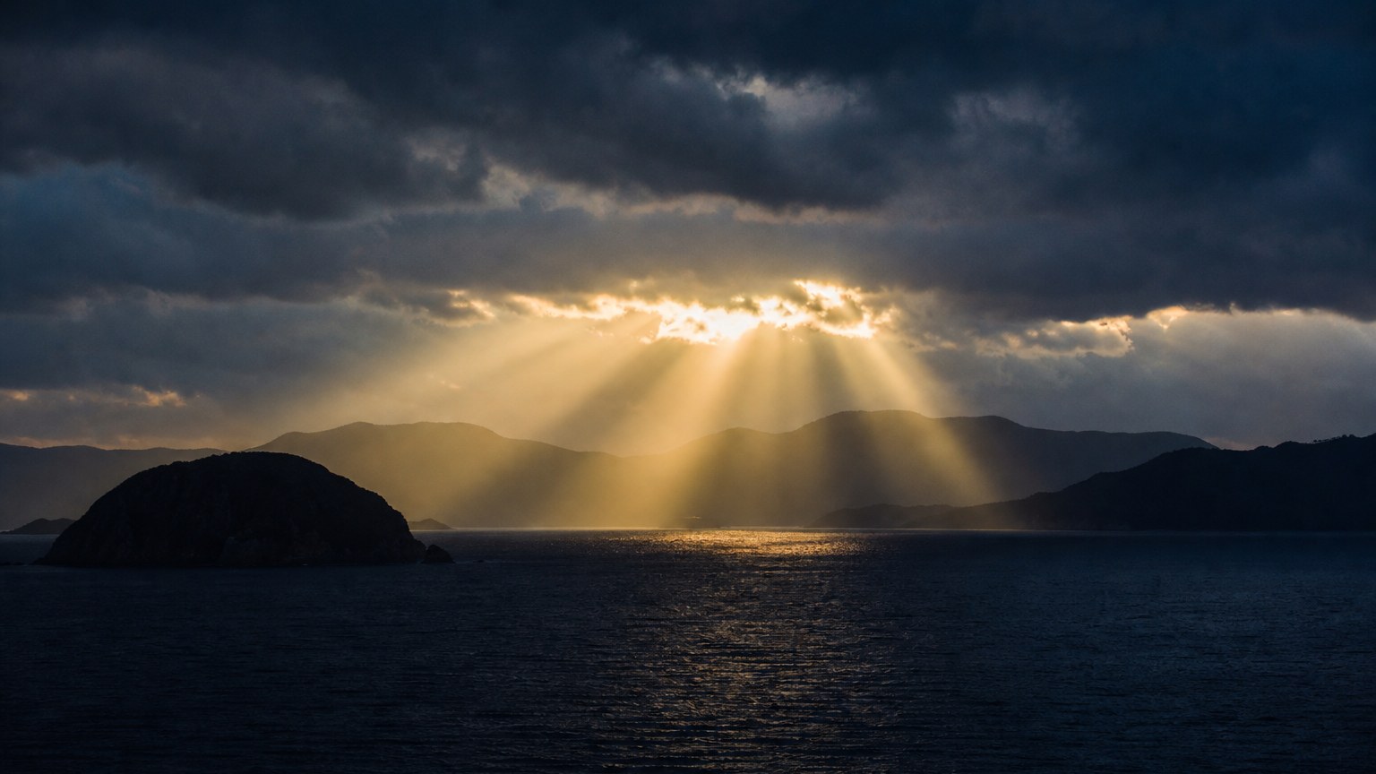 雲間から差し込む夜明けの光と海